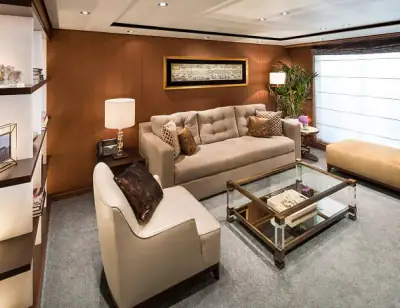 Pinnacle Suite living area with beige sofa, armchair, glass coffee table, and modern décor aboard a Holland America cruise ship.