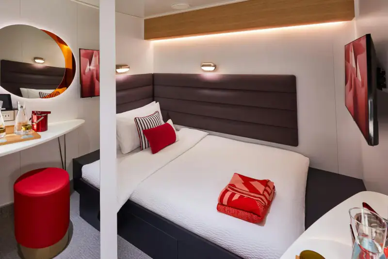 Virgin Voyages Solo Insider cabin with a bed and wood-paneled wall