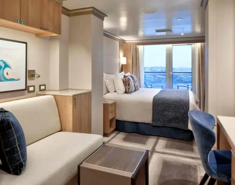 Vista Suite with queen bed, seating area, and private balcony aboard a Holland America cruise ship.