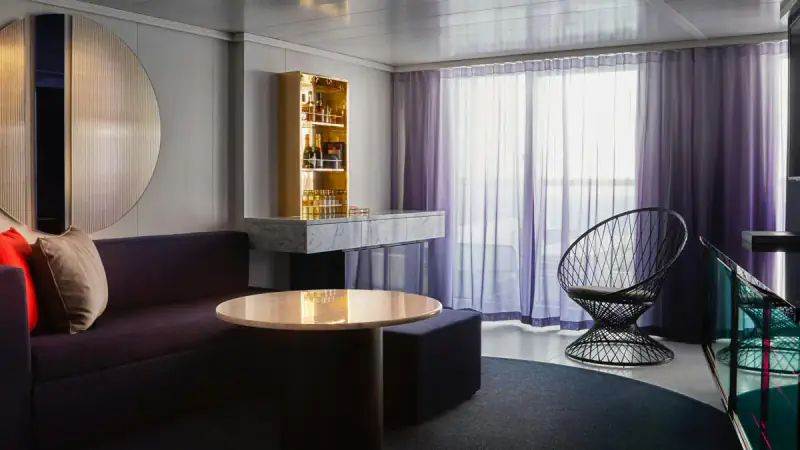 Virgin Voyages Fab Suite living room with a bar, sofa, table, and chairs