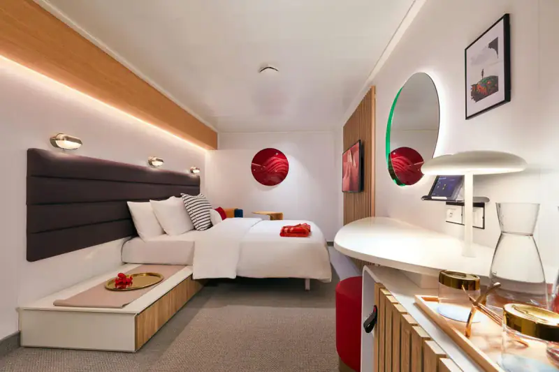 Virgin Voyages Insider cabin with a bed, sofa, and vanity