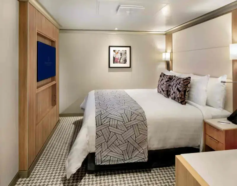 Inside stateroom with queen bed, modern décor, and soft lighting aboard a Holland America cruise ship.