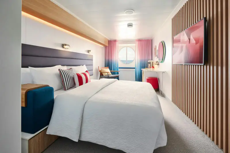 Virgin Voyages Sea View cabin with a bed and round picture window