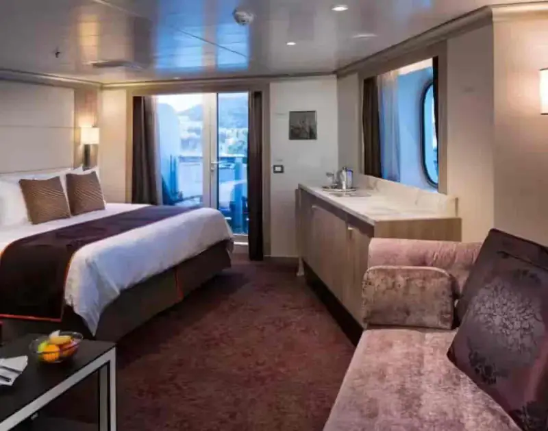 Signature Suite with king bed, sofa seating, marble countertop, and private balcony view aboard a Holland America cruise ship.