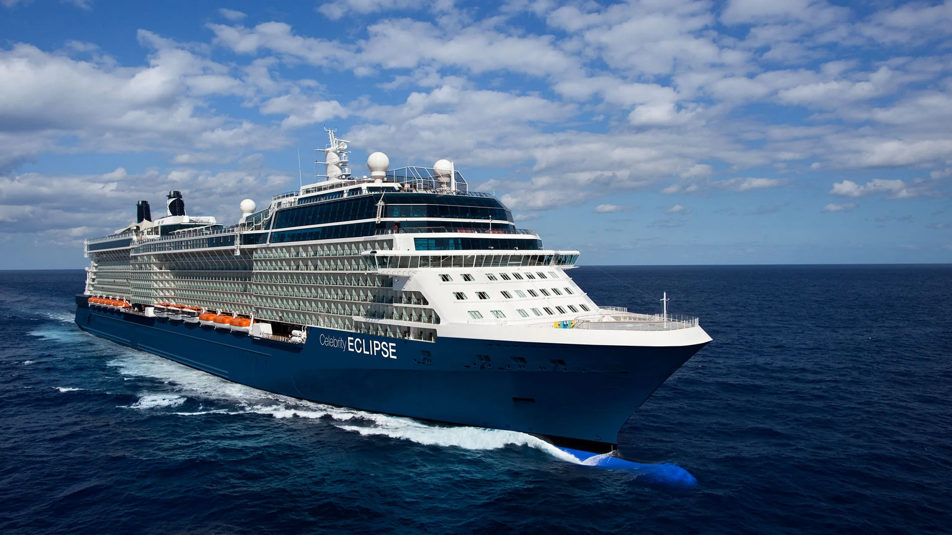 Celebrity Eclipse sailing at sea beneath a blue, cloud-dotted sky
