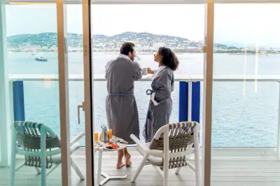 Two guests in robes having breakfast on an AquaClass veranda aboard Celebrity Reflection