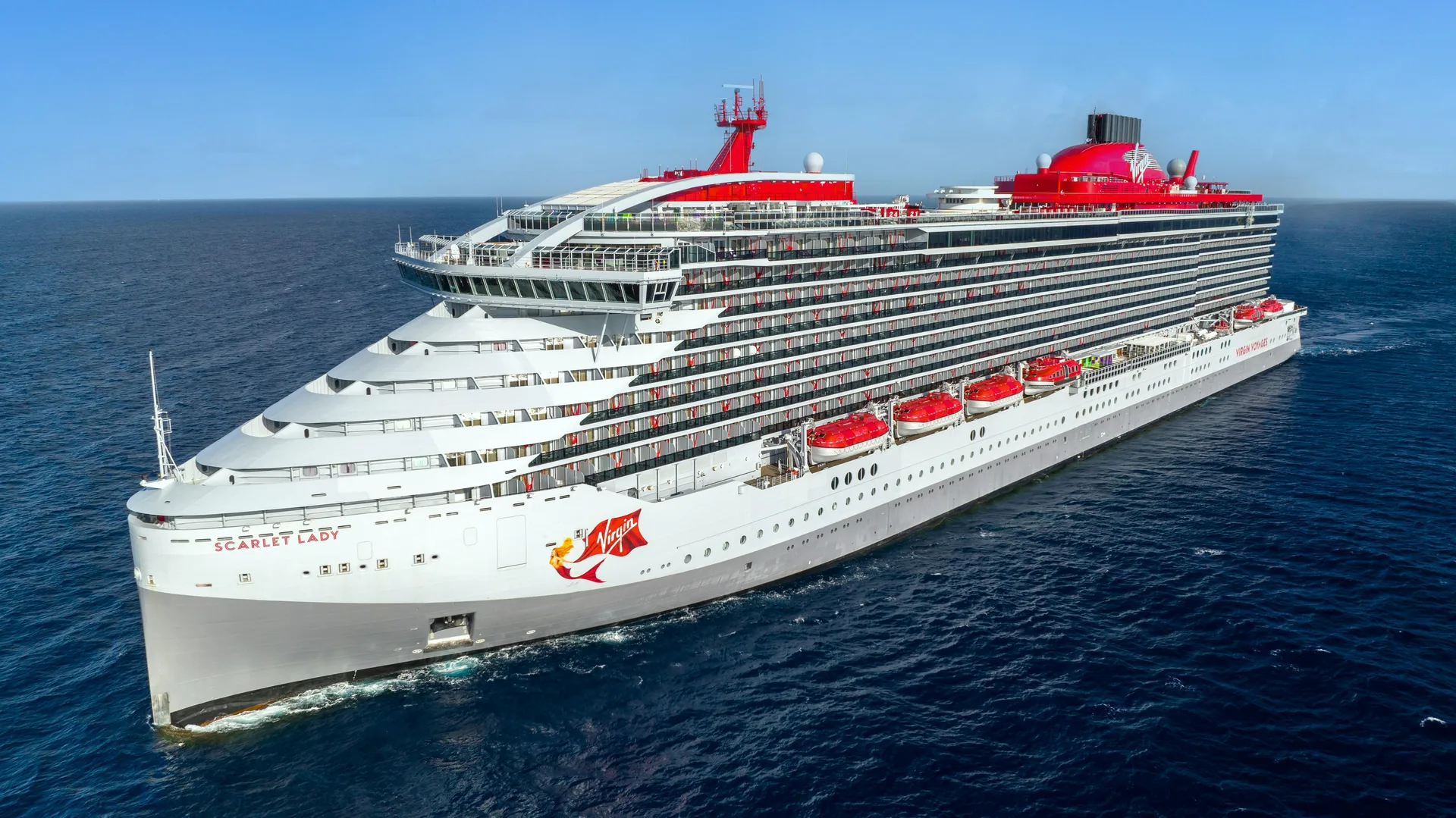 Aerial three-quarter view of Scarlet Lady sailing across blue water