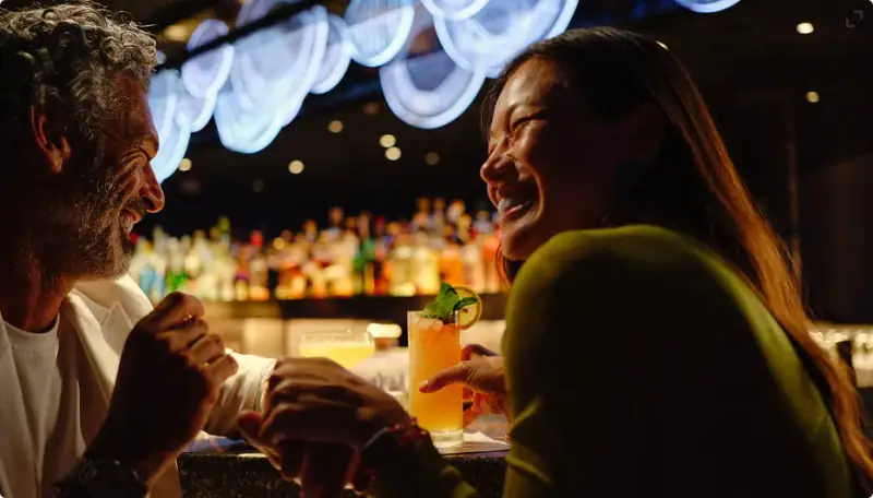 Two Sailors enjoying cocktails at a warmly lit bar aboard Scarlet Lady