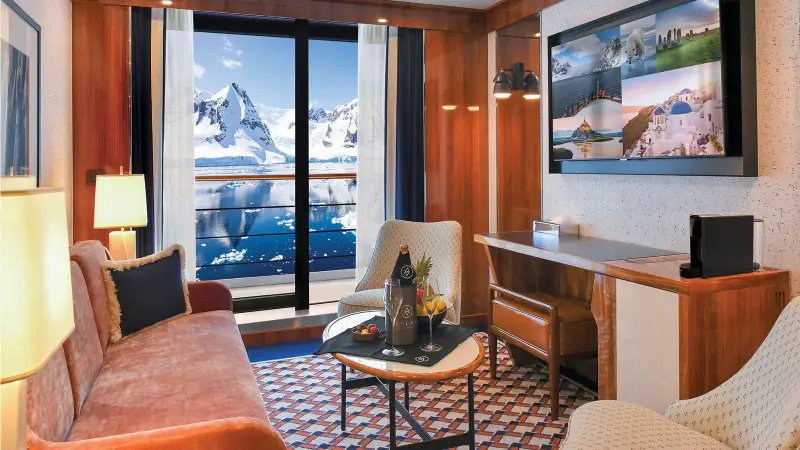 World Traveller Discovery Suite living room with sofa, desk, and veranda