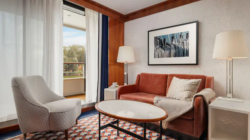 World Traveller Journey Suite living room with sofa, chairs, and veranda