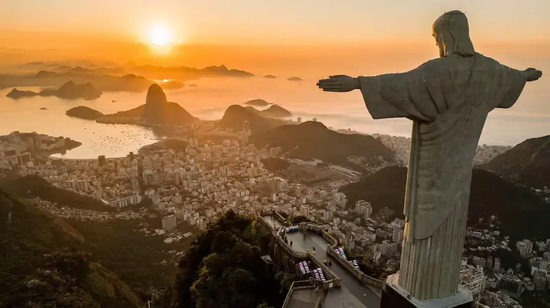 Christ the Redeemer overlooks Rio de Janeiro and its bays at sunrise.