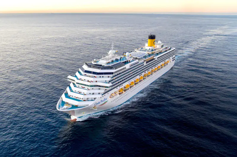 Costa Pacifica sails across calm open water in warm evening light.
