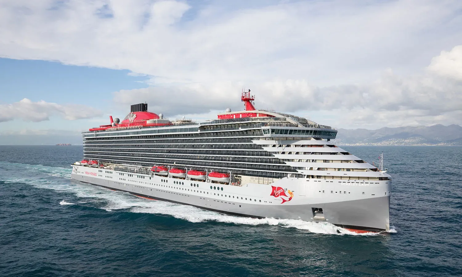 Scarlet Lady sails across open water beneath a cloudy sky.