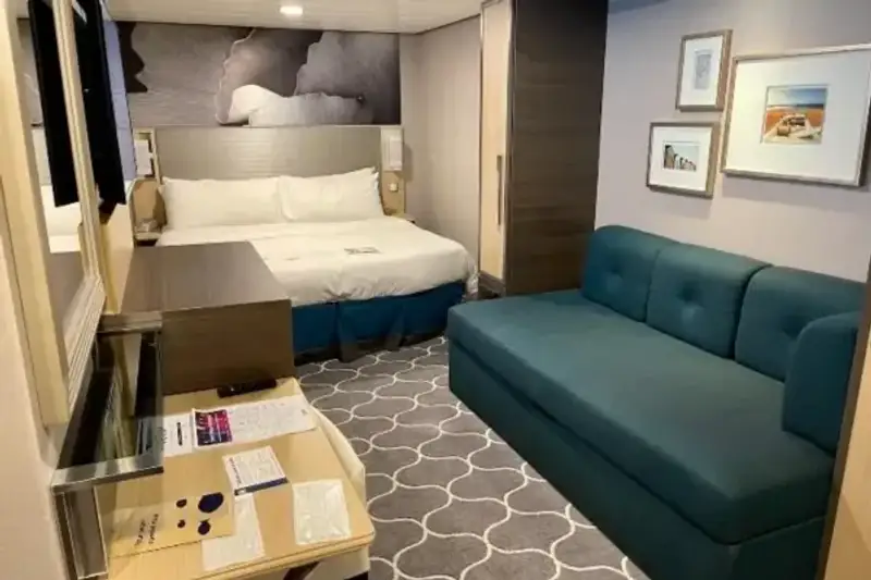A cruise-ship stateroom includes a bed, sofa, and balcony.