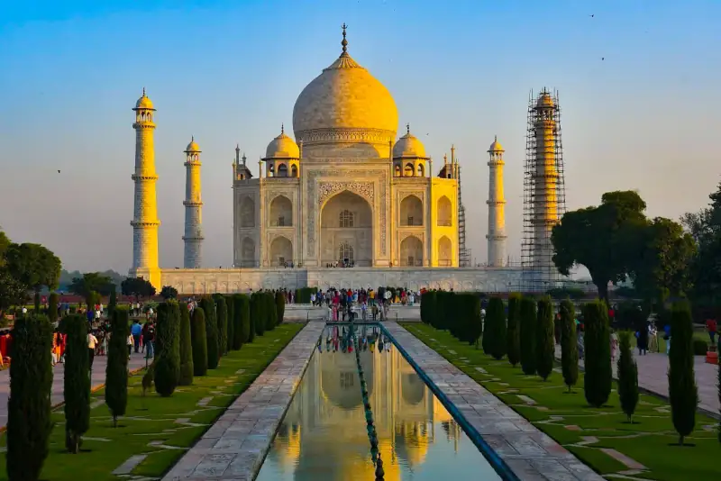 The Taj Mahal reflects in a pool at sunrise.