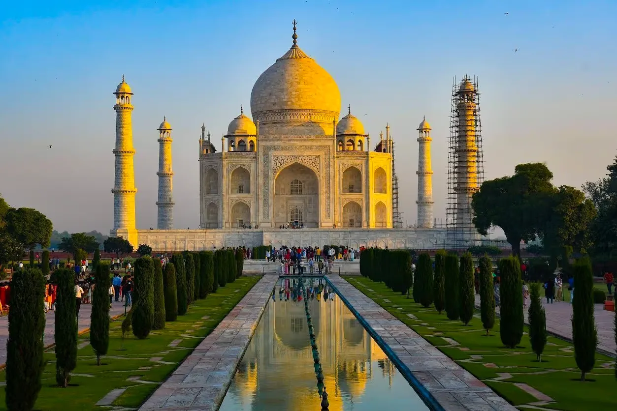 The Taj Mahal reflects in a pool at sunrise.