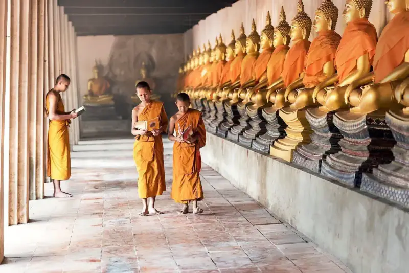 A temple interior is lined with rows of gilded Buddha statues.