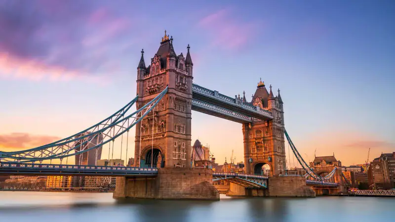 Tower Bridge spans the River Thames in London at dusk.