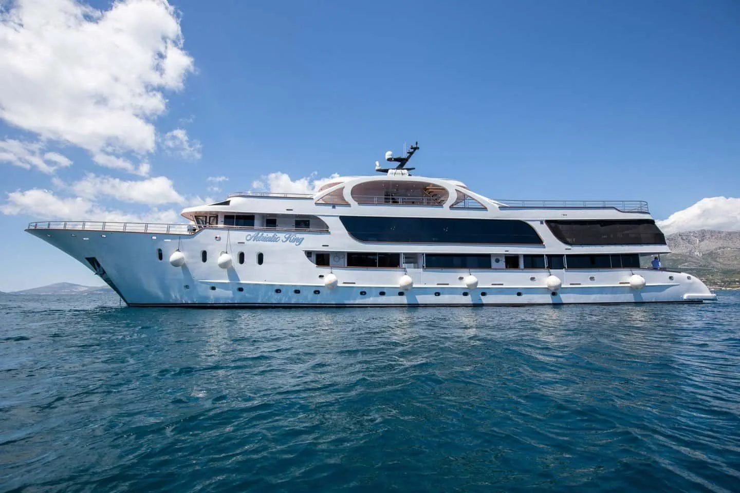 A white expedition yacht cruises across calm blue water.