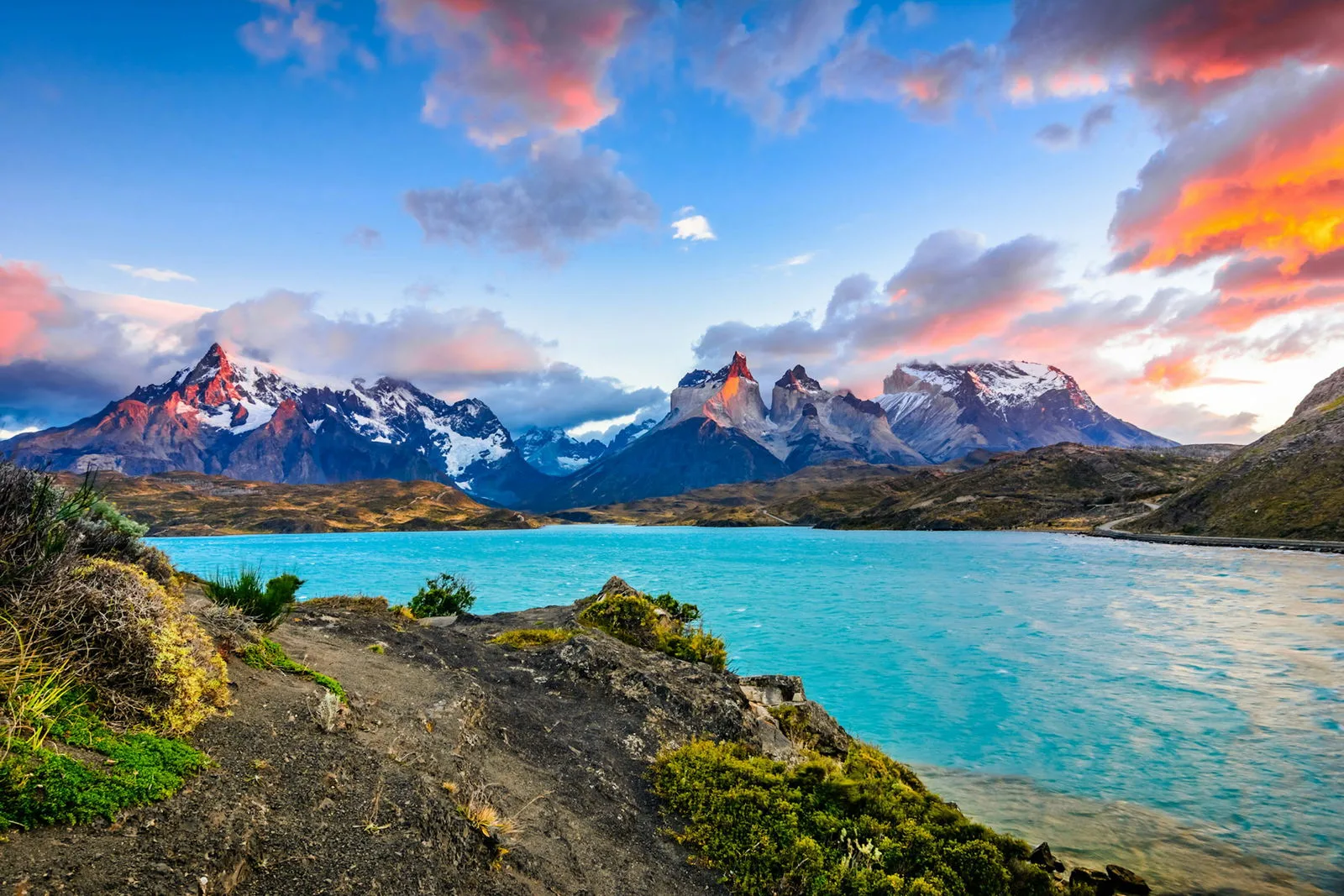 A turquoise Patagonian lake winds between rugged mountains.