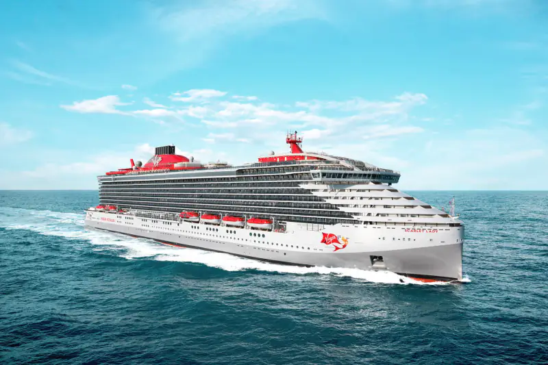 A Virgin Voyages cruise ship sails through calm blue water.