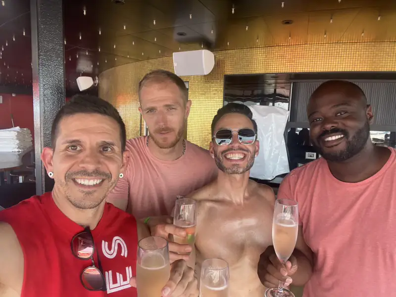 Four travelers raise sparkling-wine glasses aboard a Virgin Voyages ship.