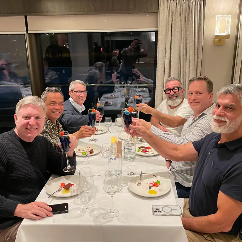 A group of travelers toast at a dinner table aboard a river cruise.