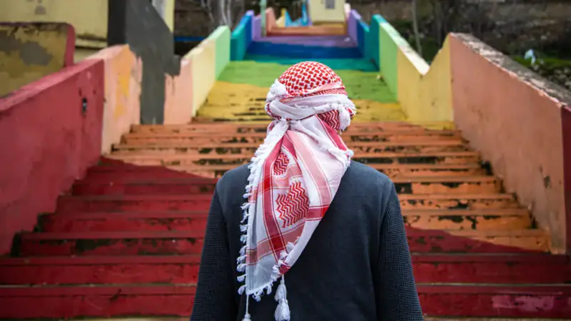 A traveler in traditional dress walks down red stairs in an Arabian Nights cruise graphic.
