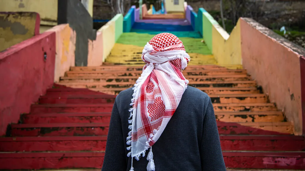 A traveler in traditional dress walks down red stairs in an Arabian Nights cruise graphic.
