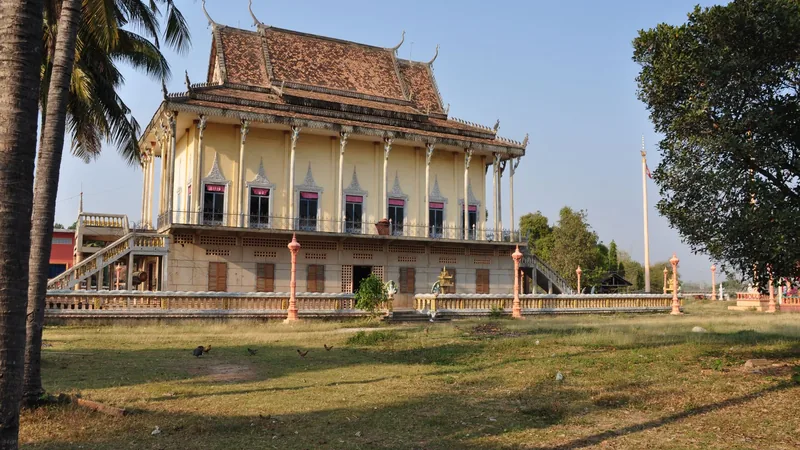 A monastery building and palm-lined grounds in Angkor Ban beside the Mekong