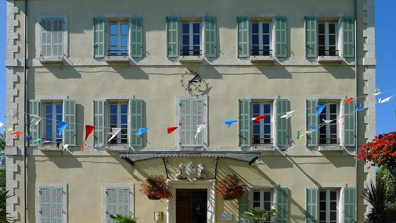 Châteauneuf-du-Rhône town hall façade with green shutters, clock and decorative bunting