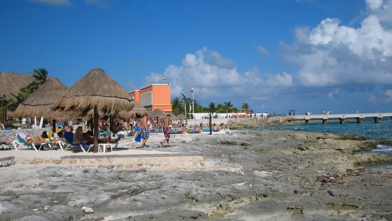 Costa Maya beach, palms, and orange lighthouse under a blue sky