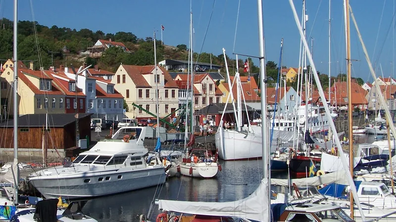 Yachts and red-roofed waterfront houses in Gudhjem harbor in a historical 2006 view; not a cruise berth map