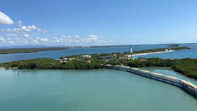 Harvest Caye's pier, beach, lagoon, and green southern Belize coast seen from a cruise ship