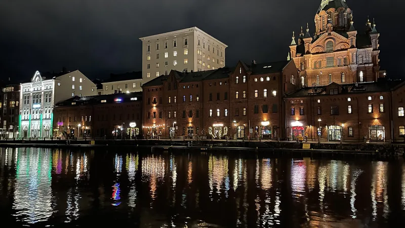 Illuminated waterfront buildings and Uspenski Cathedral in Helsinki’s Katajanokka, reflected in the water at night