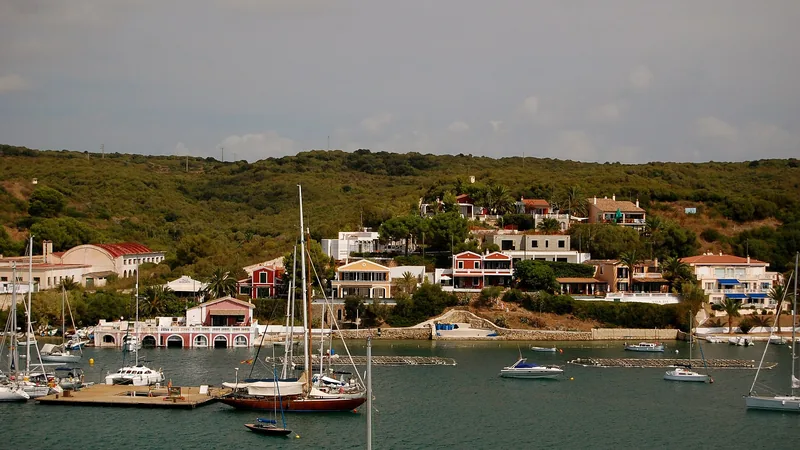 Sailboats and colorful waterfront homes around Mahón's natural harbor