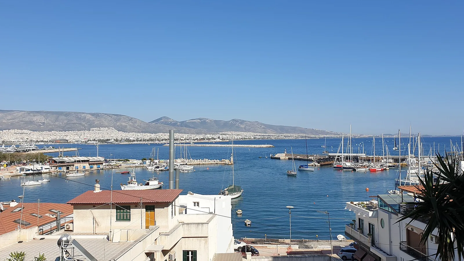 Mikrolimano harbor in Piraeus with boats, waterfront homes, and hills