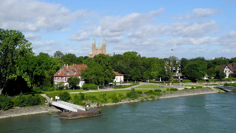 Speyer Cathedral above riverside buildings and a Rhine passenger pontoon in a historic photograph