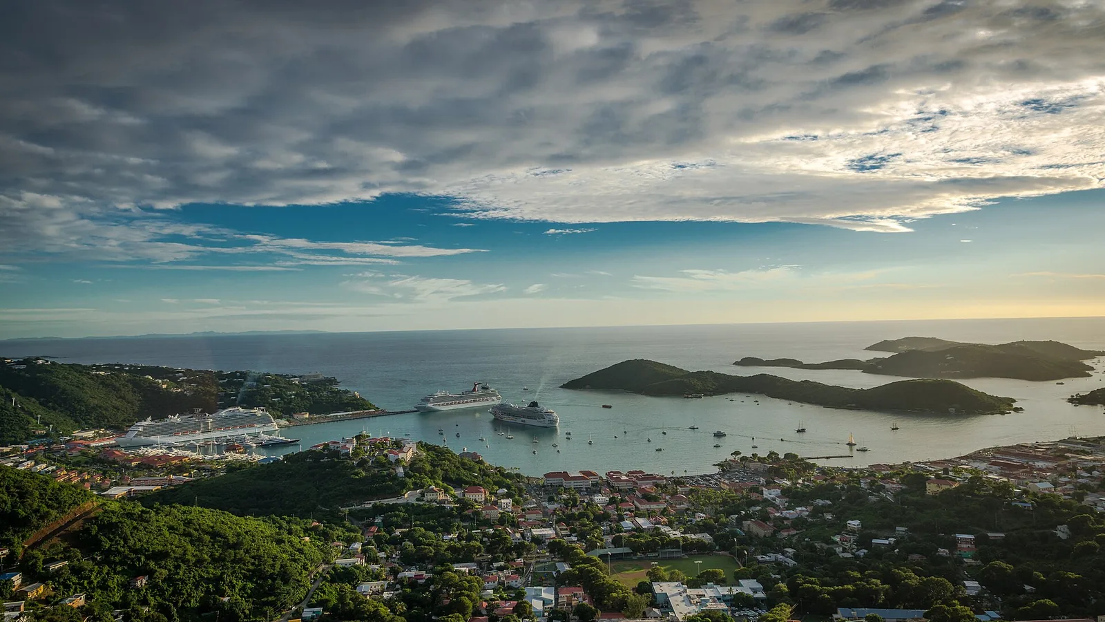 Charlotte Amalie harbor, green hills, and islands under dramatic clouds