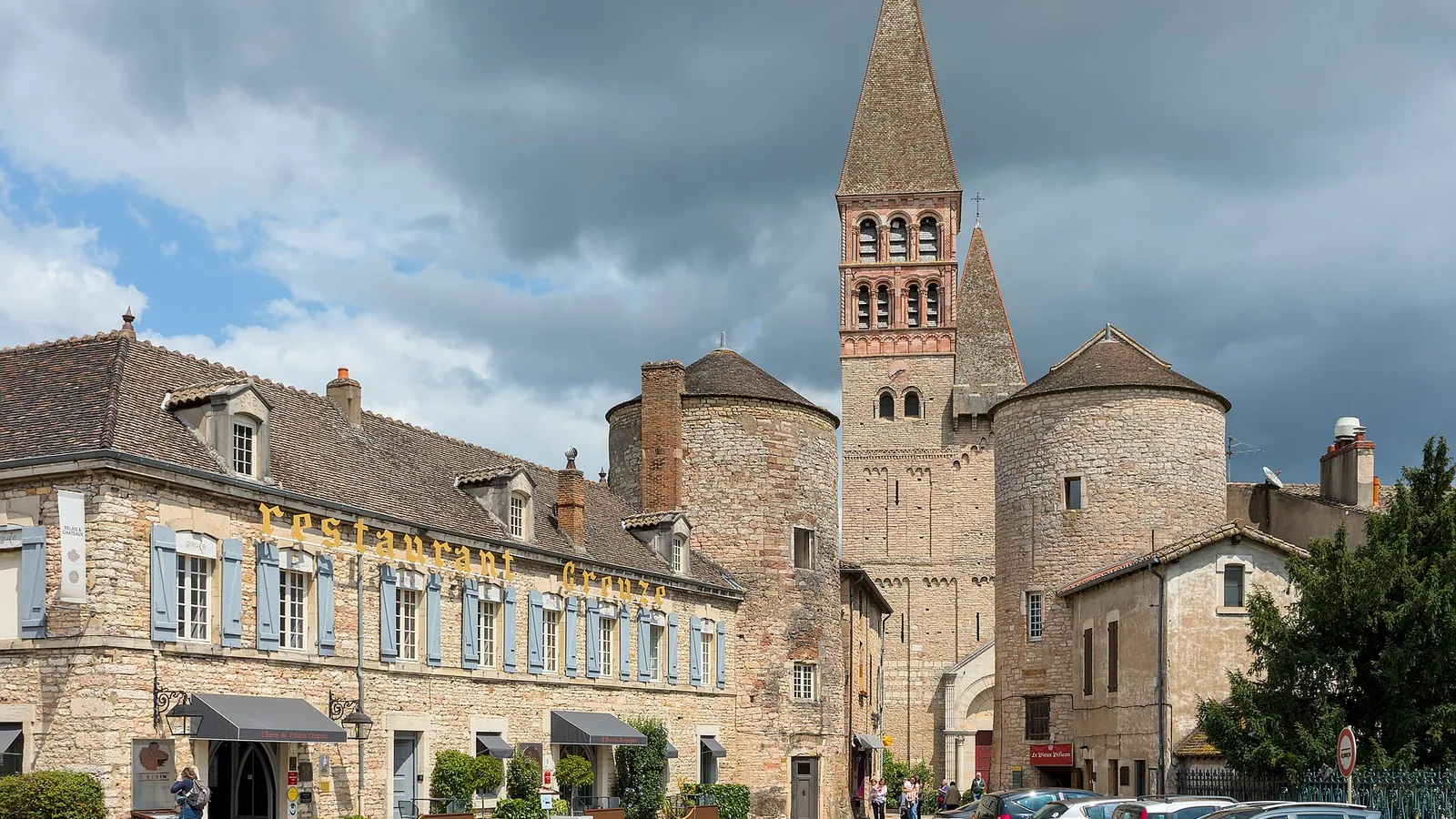 Saint-Philibert abbey church and entrance towers in Tournus, with nearby buildings and visitors