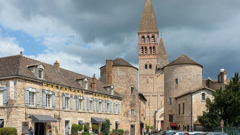 Saint-Philibert abbey church and entrance towers in Tournus, with nearby buildings and visitors
